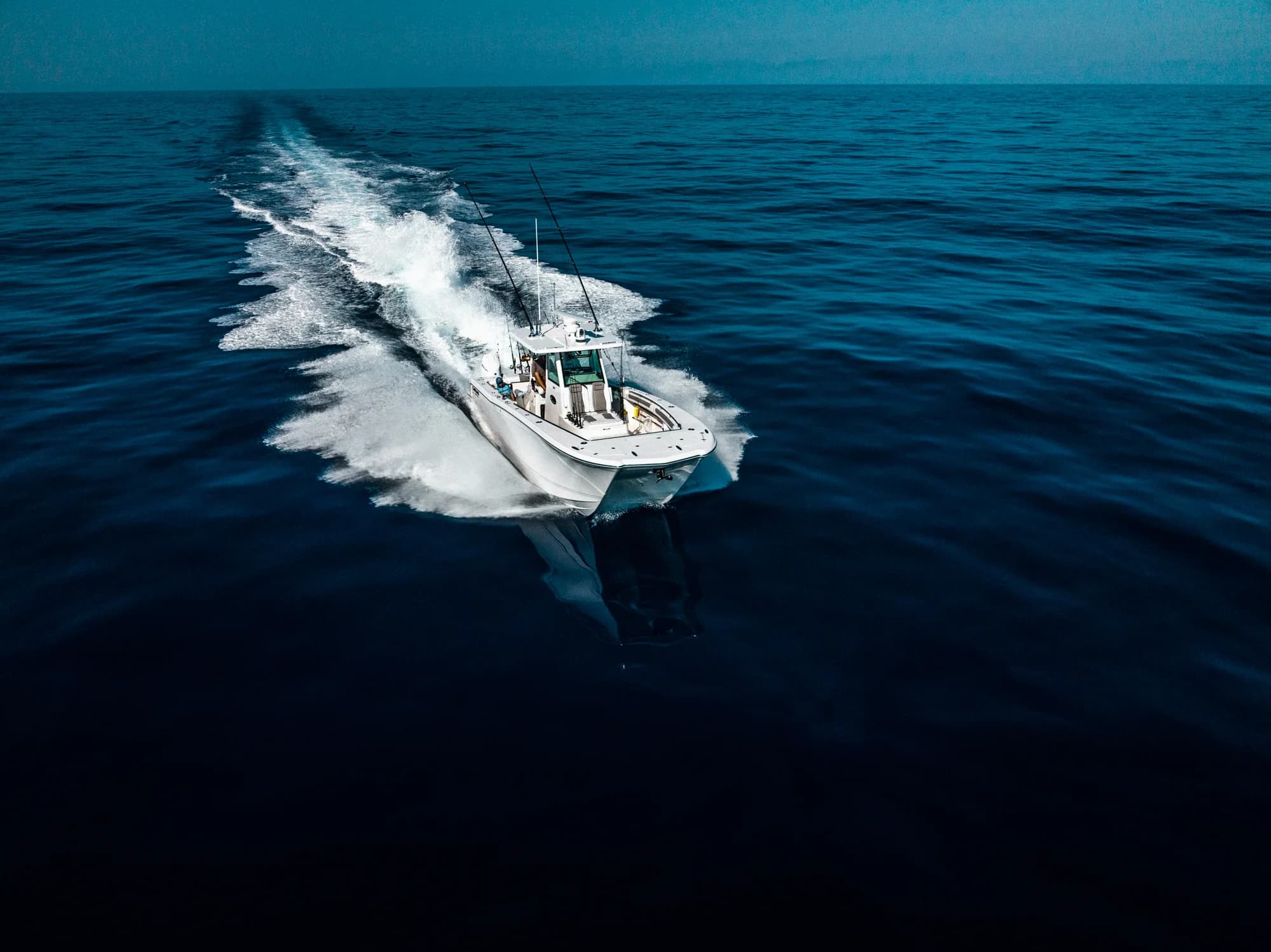 Aerial view of a sportfishing boat cutting through dark ocean water